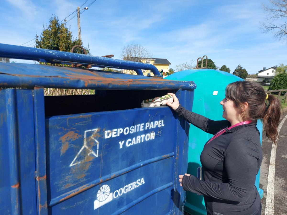 Paloma Pérez tira cartón a un contenedor azul en Mohías.