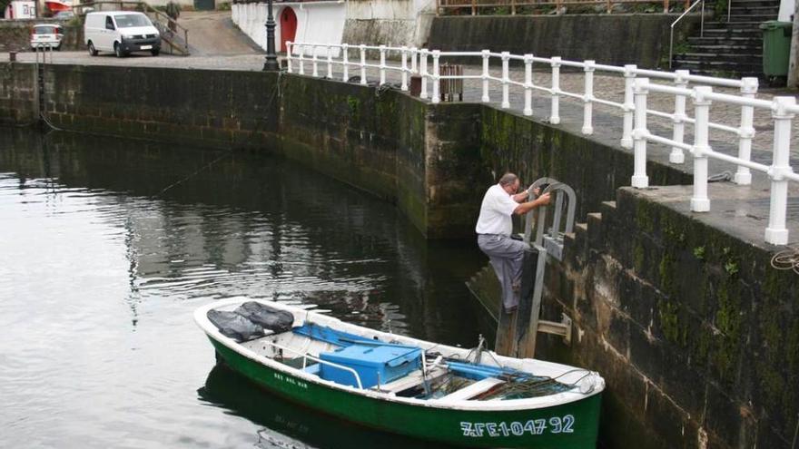 Un vecino accede a su embarcación en el puerto de Viavélez.