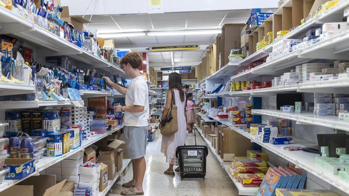 Varias personas compran material escolar en una gran superficie comercial.