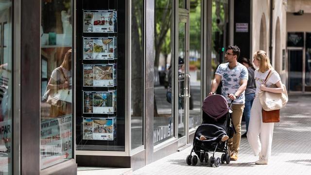 Dos personas observan los anuncios de viviendas en venta en una inmobiliaria en Palma.