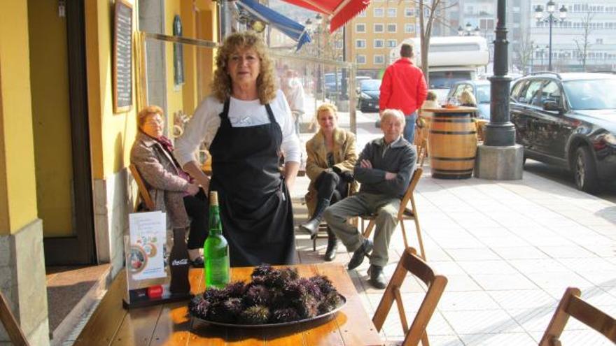 Paloma Aladro, del restaurante El Llagar de Ribadesella, junto a una bandeja de arcinos y una botella de sidra. En la otra imagen, varios empresarios degustan el emberzao. | p. m.