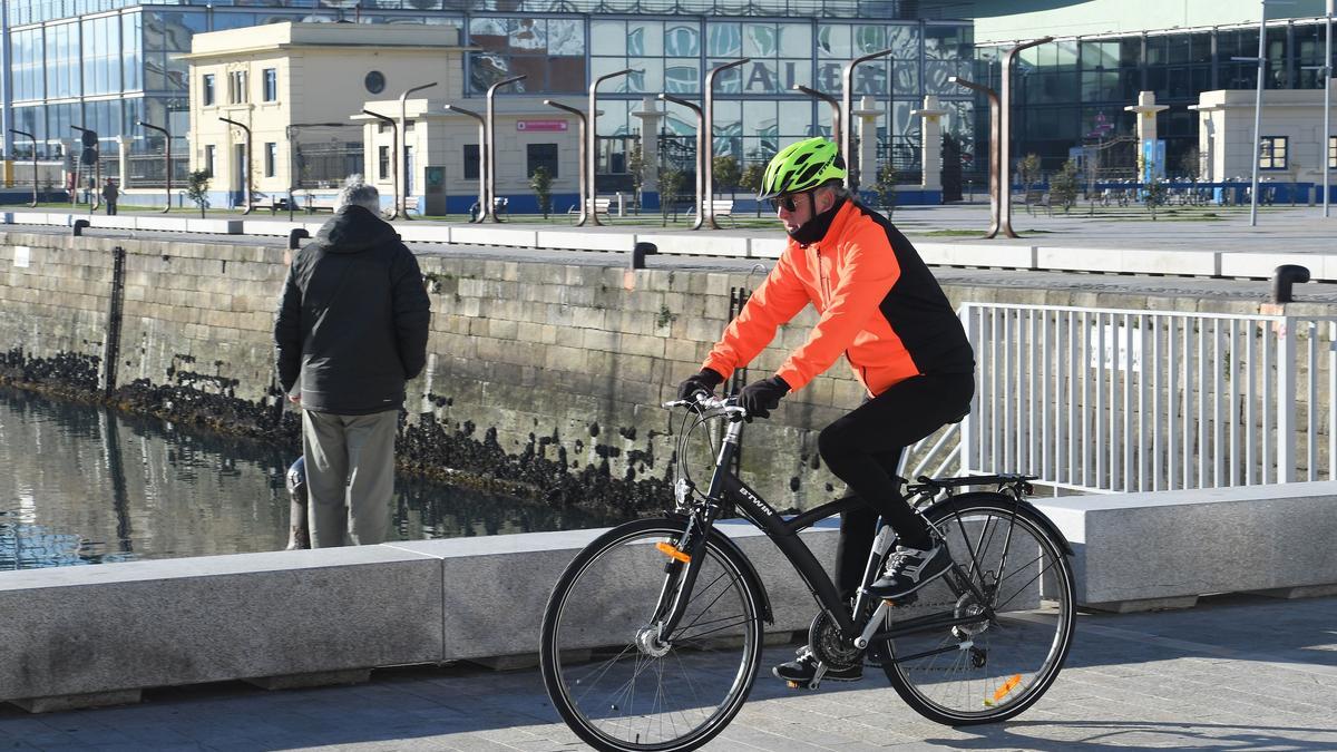 Un ciclista circula por la Marina de A Coruña un día soleado.