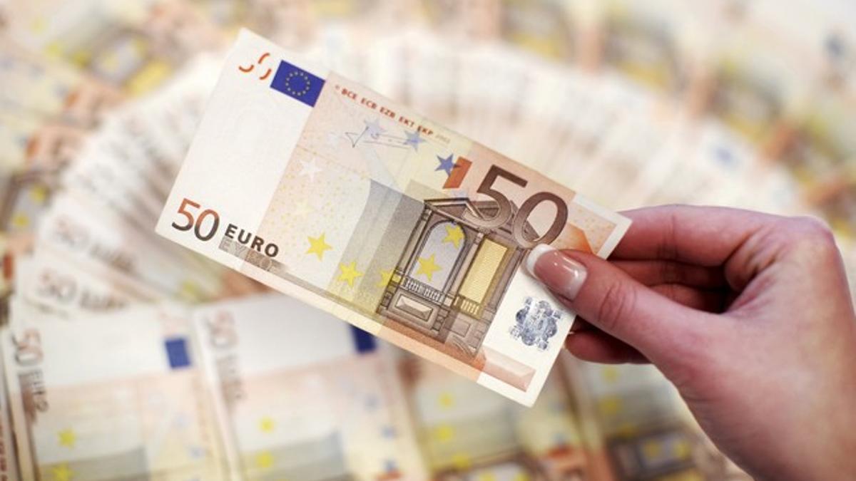 Imagen de archivo. Un empleado de un banco enseña 50 euros