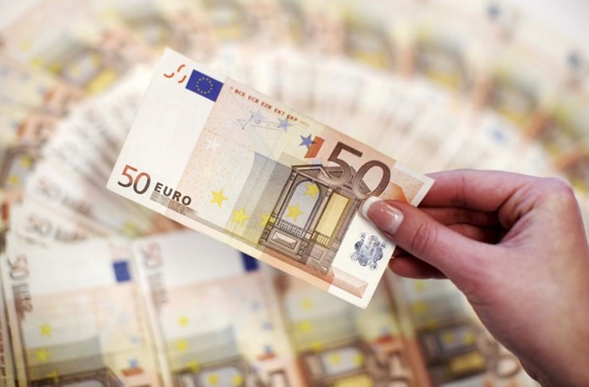 Imatge d’arxiu. Un empleat d’un banc ensenya 50 euros. Imatge d’arxiu. Un empleat d’un banc ensenya 50 euros.