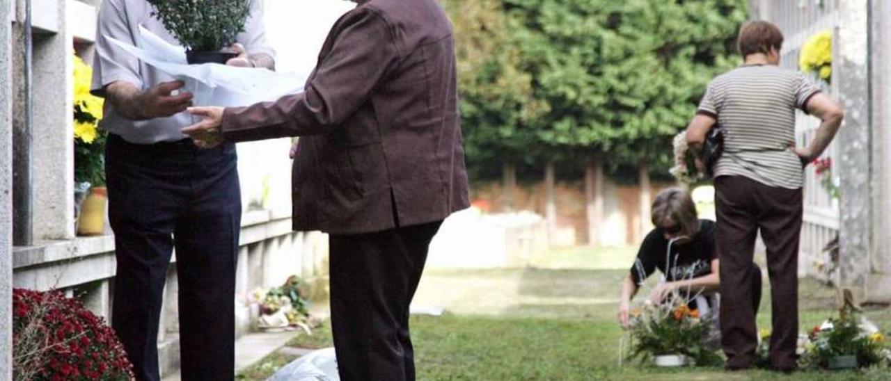 Vecinos colocan flores en panteones del cementerio de A Romea. // Bernabé/Luismy