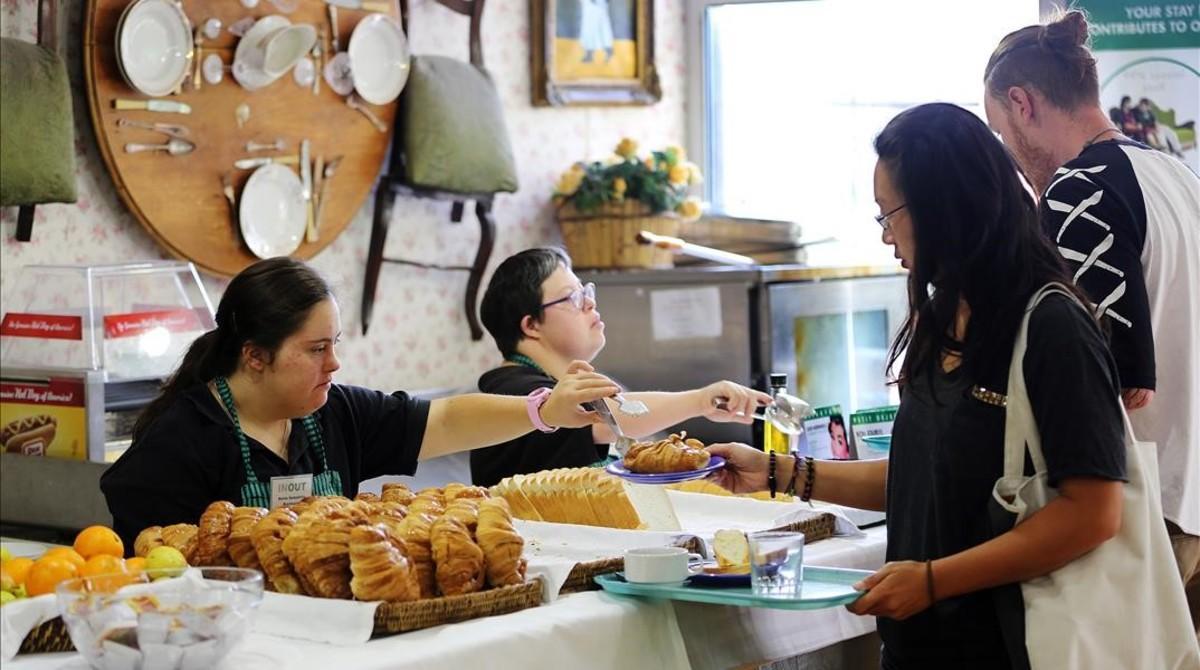 Dos jóvenes con síndrome de Down atienden a los clientes de una panadería en Barcelona.