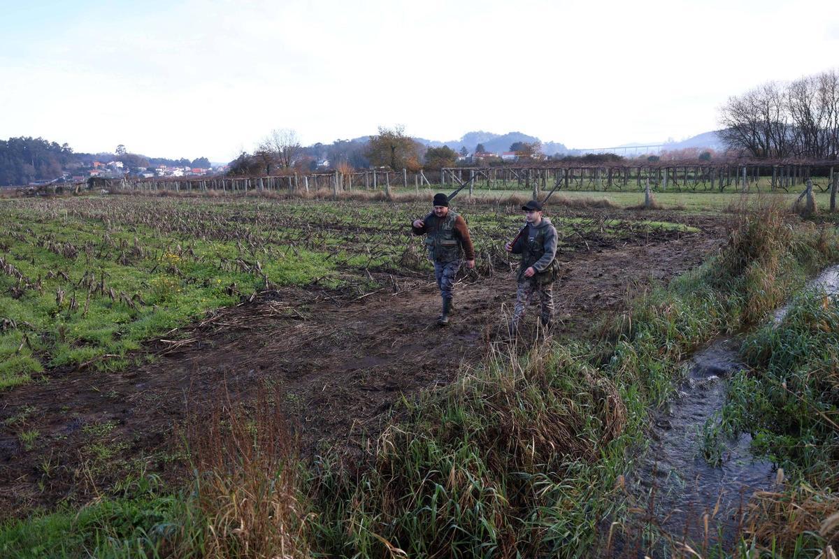 Dos aficionados pasean a orillas de un arroyo, ayer en Portas.