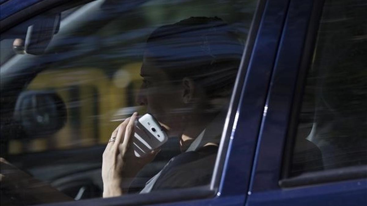 Un conductor usa el teléfono mientras circula por el Eixample de Barcelona.