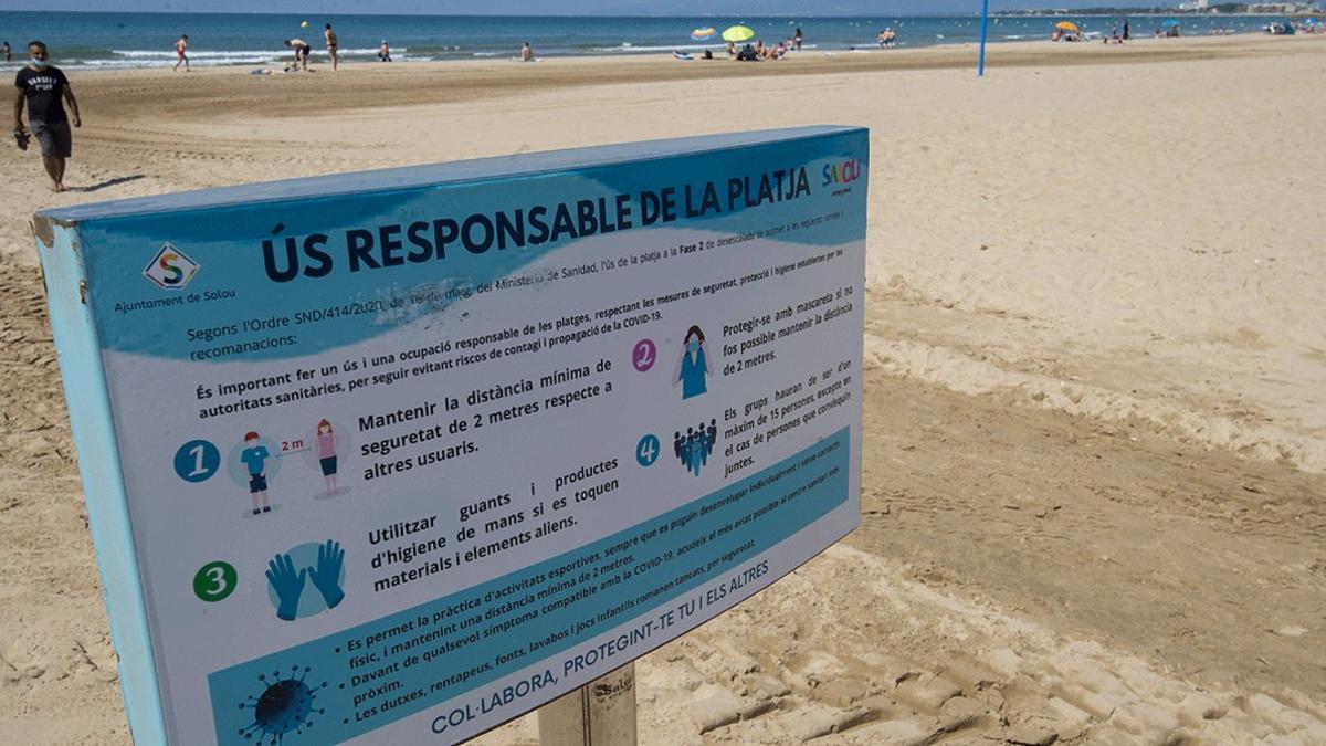 Cartel informativo con medidas anticovid, en una playa de Salou, el pasado 30 de mayo