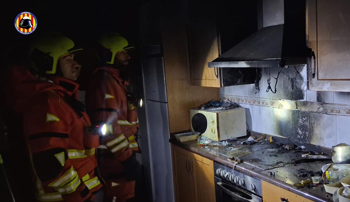 Dos bomberos, en la cocina de la vivienda afectada por el fuego.