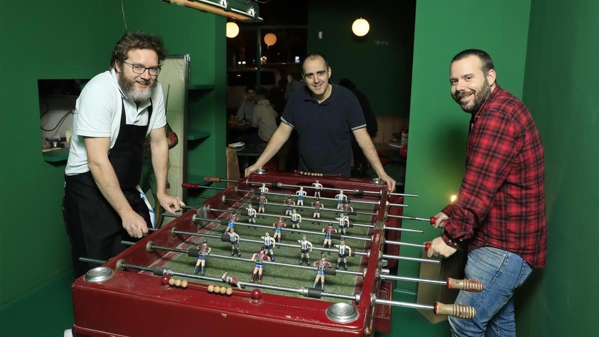 Rafa Peña, Juanlu Pérez (en el centro) y Biel Gavaldà, le dan al futbolín en el Bar Torpedo.