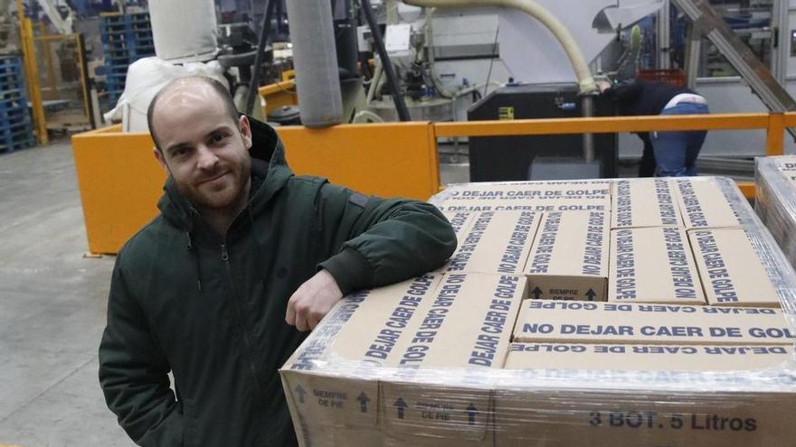 José Luis Caravia, junto a una carga de cajas con botellas de lejía, en la fábrica de la compañía, en Sariego.