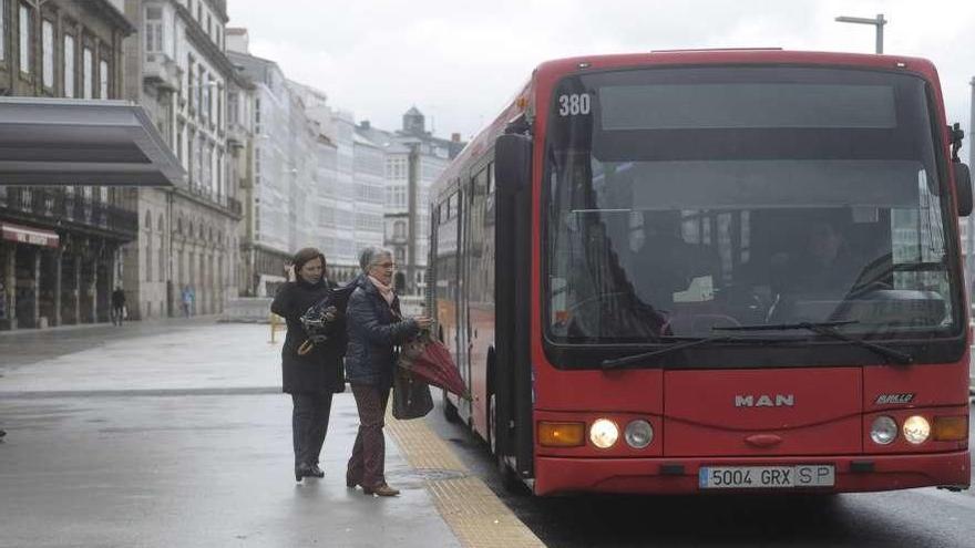Usuarias de A Coruña suben al bus urbano en la Marina, donde para la línea 1A.