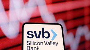 El logo de SVB en un teléfono móvil y junto a un panel.
