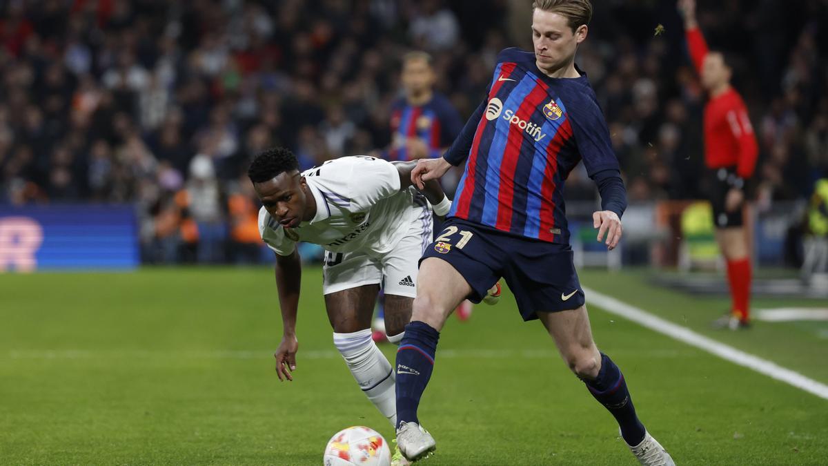 MADRID, 02/03/2023.- El centrocampista del Barcelona Frenkie De Jong (i) escapa de Vinicius Junior, del Real Madrid, durante el partido de ida de las semifinales de la Copa del Rey que Real Madrid y FC Barcelona disputan este jueves en el estadio Santiago Bernabéu. EFE/Juanjo Martín