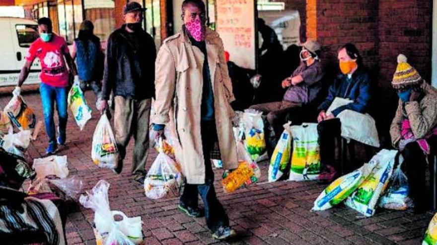Varias personas con bolsas de comida en Sudáfrica.