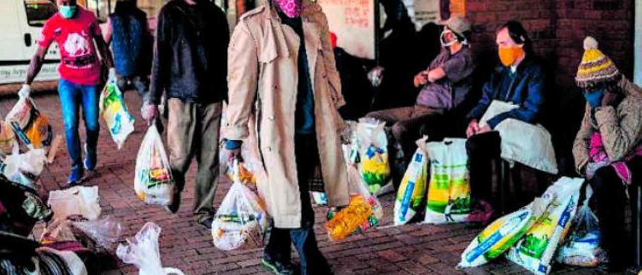 Varias personas con bolsas de comida en Sudáfrica.