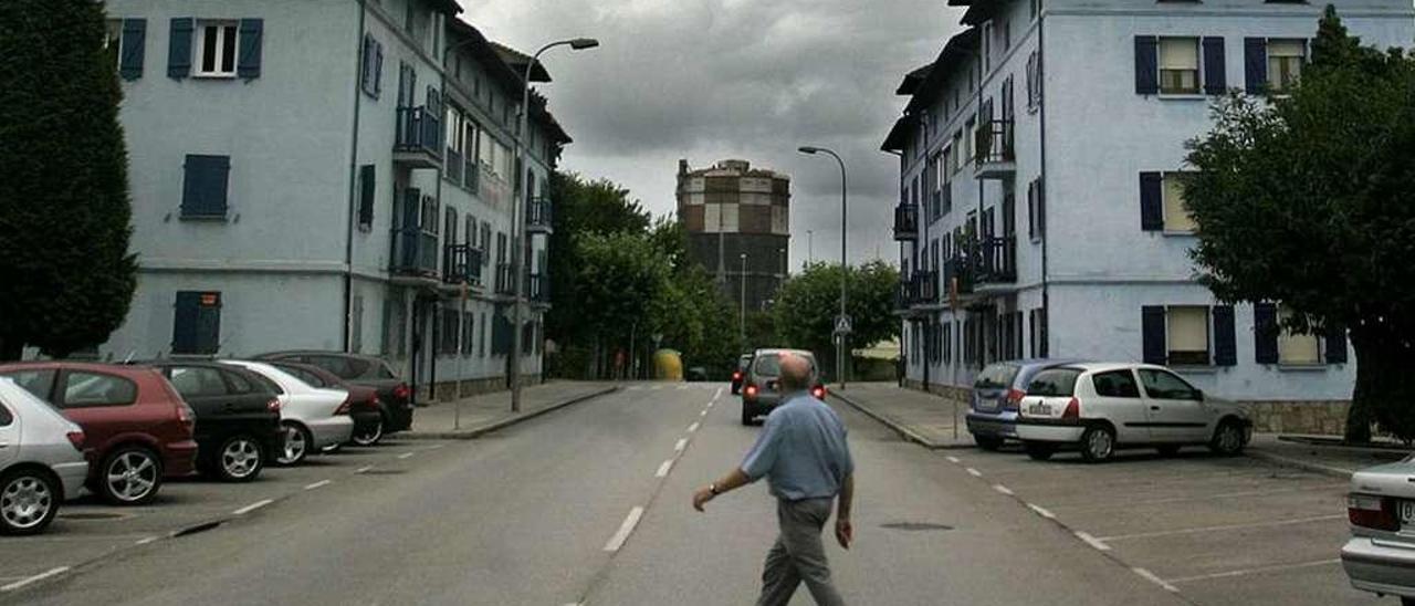 Un hombre cruza la calle Gijón de Llaranes, con un gasómetro al fondo de la imagen.