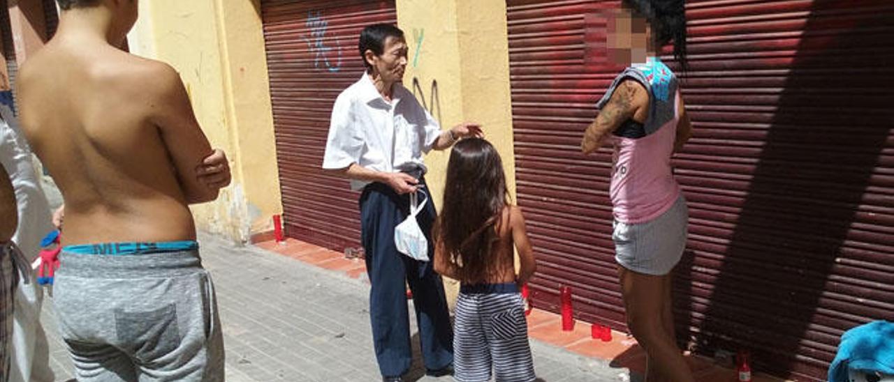 El padre de la detenida conversa con una vecina en la puerta del negocio familiar.