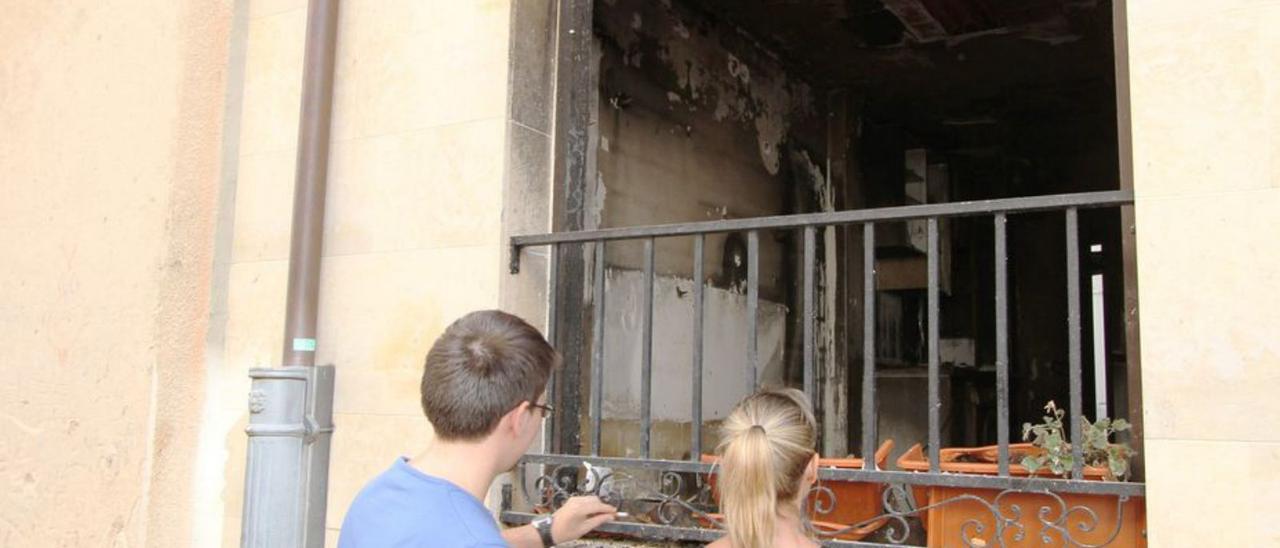 Dos jóvenes contemplan los daños en una casa incendiada.