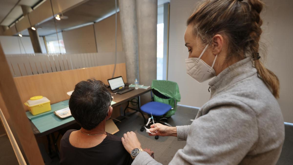 Una sanitaria vacuna a un joven.