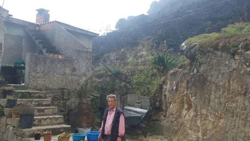 José Davila, ayer, junto a su vivienda pegada a una ladera calcinada del Monte Alba. // FdV