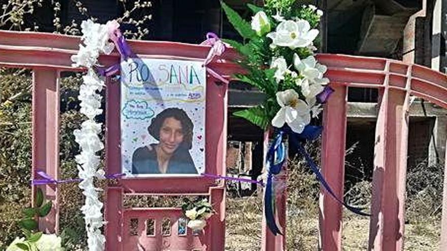 Flores junto a una valla con la foto de la mujer fallecida.