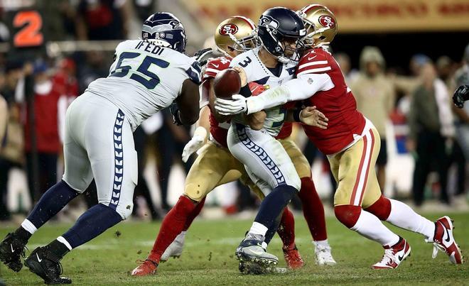 Russell Wilson # 3 de los Seattle Seahawks y Solomon Thomas # 94 de los San Francisco 49ers en el último cuarto del partido en el estadio Levis Stadium en Santa Clara, California.