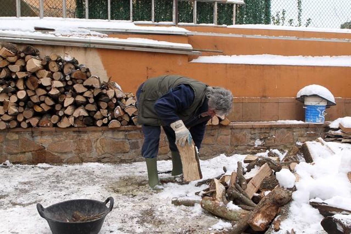 Una dona apila la llenya a Begur (Baix Empordà).