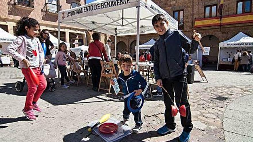 Tres niños juegan con juguetes de madera en la plaza Mayor.