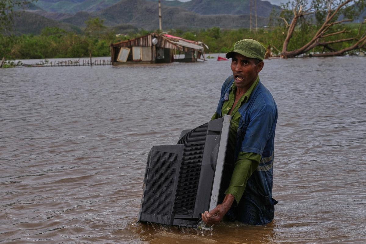 Un hombre transporta una televisión en medio de las inundaciones provocadas por el huracán "Melissa" en Santiago de Cuba, el pasado octubre.