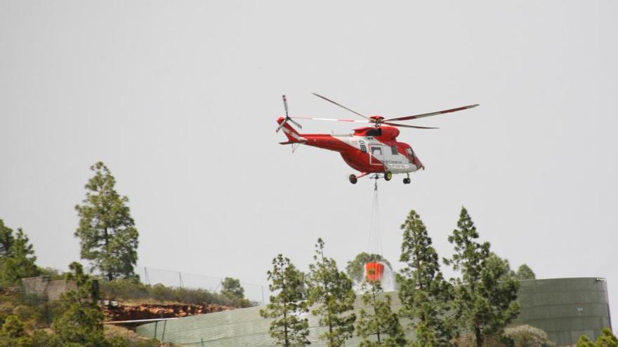 Uno de los helicópteros que trabaja en las labores de extinción recoge agua para apagar el incendio de Arico.