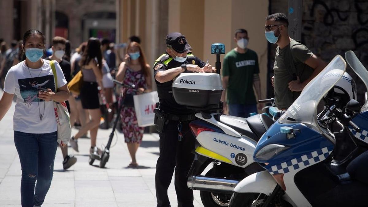 GRAF6360  BARCELONA  11 07 2020 - Un policia multa a un ciclista por una infraccion cometida y le advierte tambien de la obligatoriedad de llevar mascarilla cuando se viaja  hoy en el centro de la ciudad en este segundo fin de semana de  nueva normalidad  EFE Marta Perez