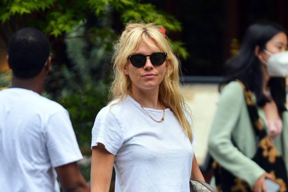 Sienna Miller con lazo rojo en el pelo y camiseta blanca