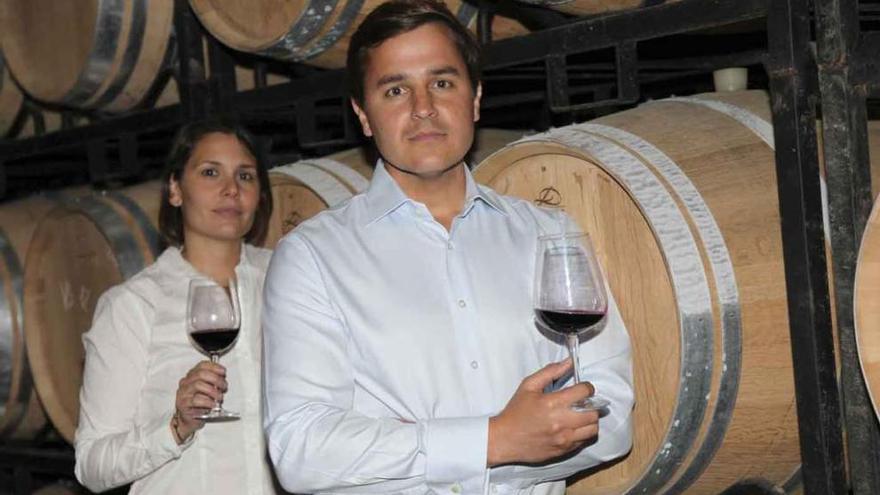 Enriqueta Celemín y Diego Ribbert posan con una copa de vino en la nave de barricas.