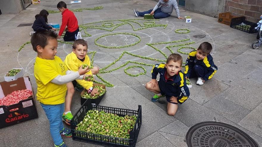 Unos niños elaboran una alfombra floral, esta tarde, en las calles de Vilavella. / FdV