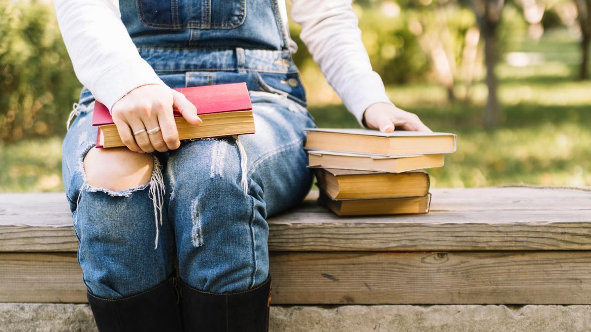 Persona sentada en una mesa con libros en el parque.