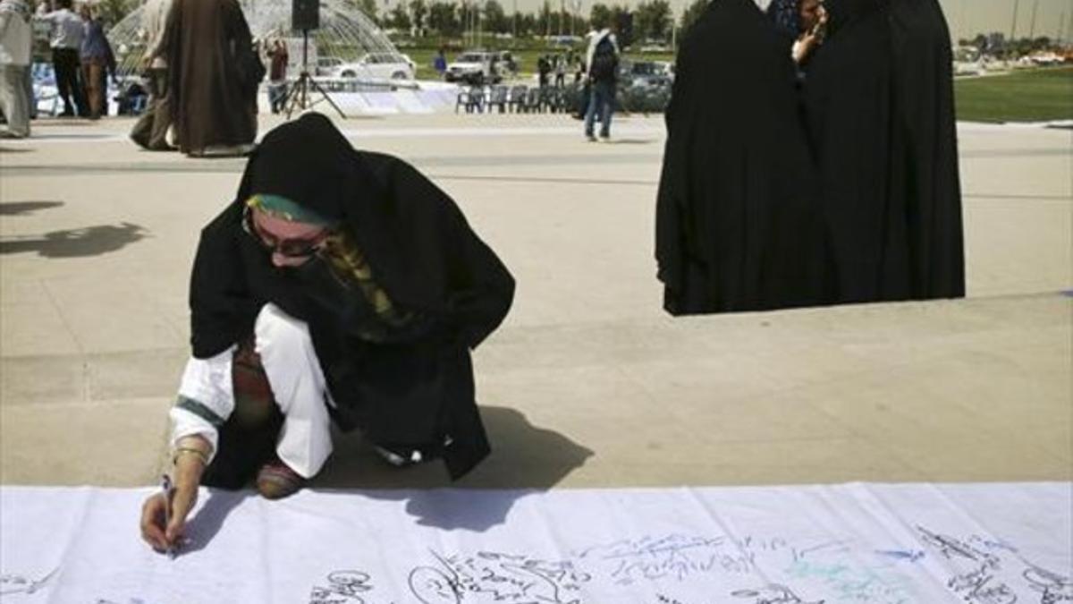 Una mujer firma una petición durante una manifestación de los partidarios de la línea dura, que exigen un «buen acuerdo» a los negociadores iranís.