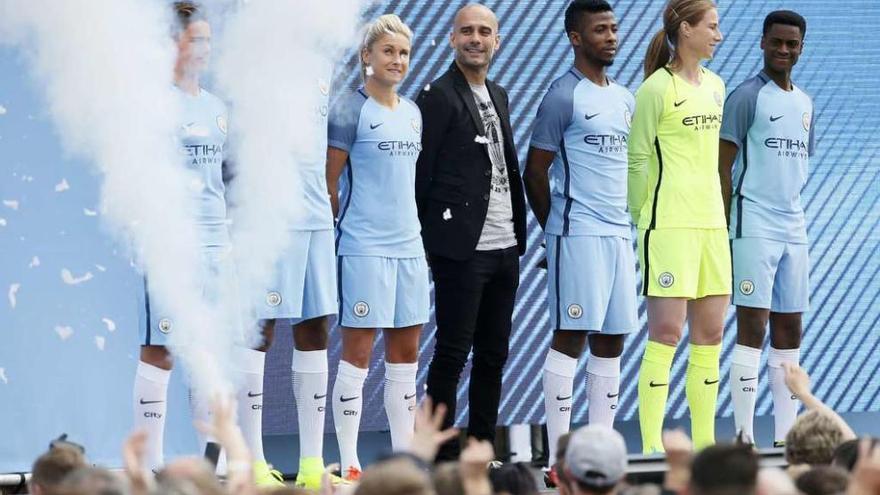 Guardiola posa con futbolistas del City luciendo los nuevos equipajes del club. // Craig Brough