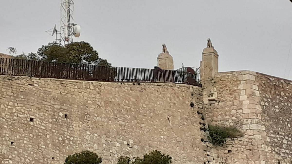 Dos personas ante la puerta de los leones cerrada