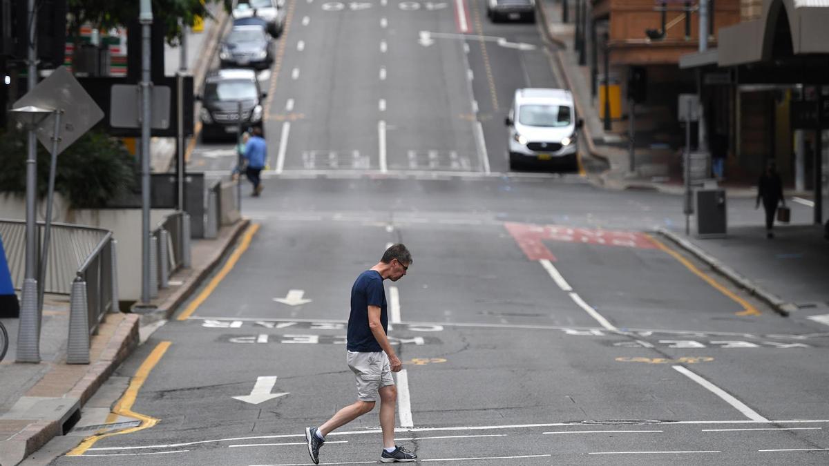 Un hombre cruza una calle casi vacía en Brisbane.