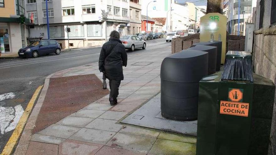 Una mujer pasa frente a un contenedor de recogida de aceite doméstico usado en Culleredo.  // FdV