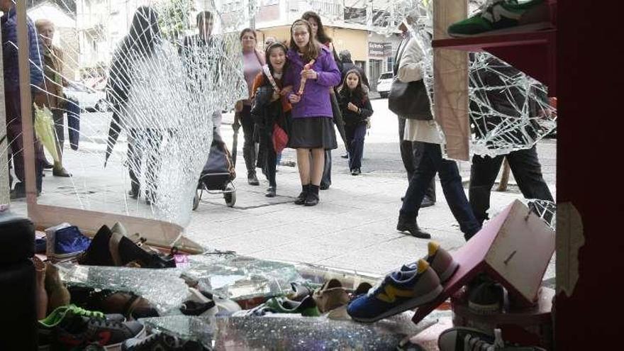 Un grupo de personas observan los daños en el escaparate de la zapatería.  // Jesús de Arcos