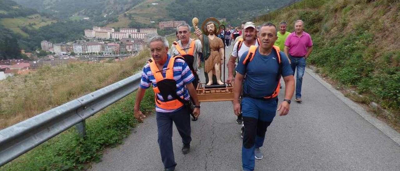 Por la izquierda, Samuel López, Faustino Rodríguez, Eloy Leiguarda y Manuel Suárez llevan a San Juan por la carretera del Acebo, seguidos de una veintena de peregrinos.