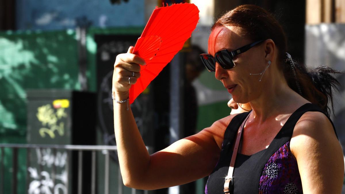 Una zaragozana se protege del calor con un abanico