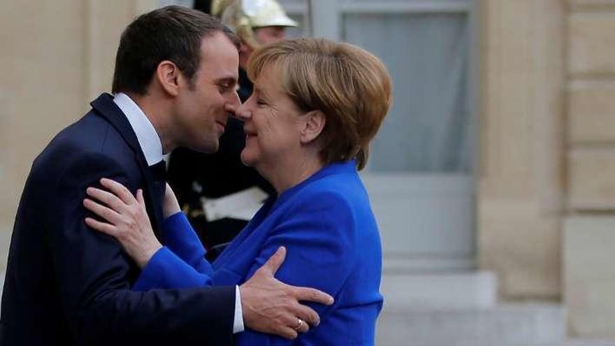 Macron recibe con un beso a la canciller Merkel. // Reuters