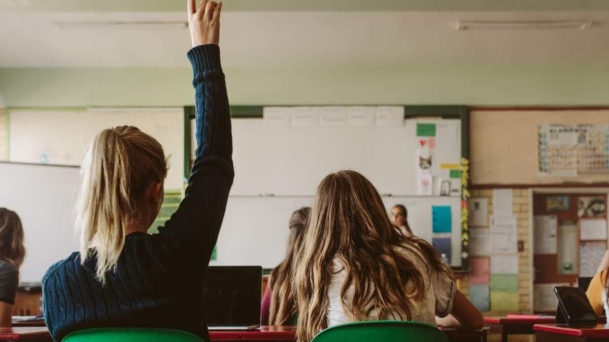 Una alumna levanta la mano en clase.