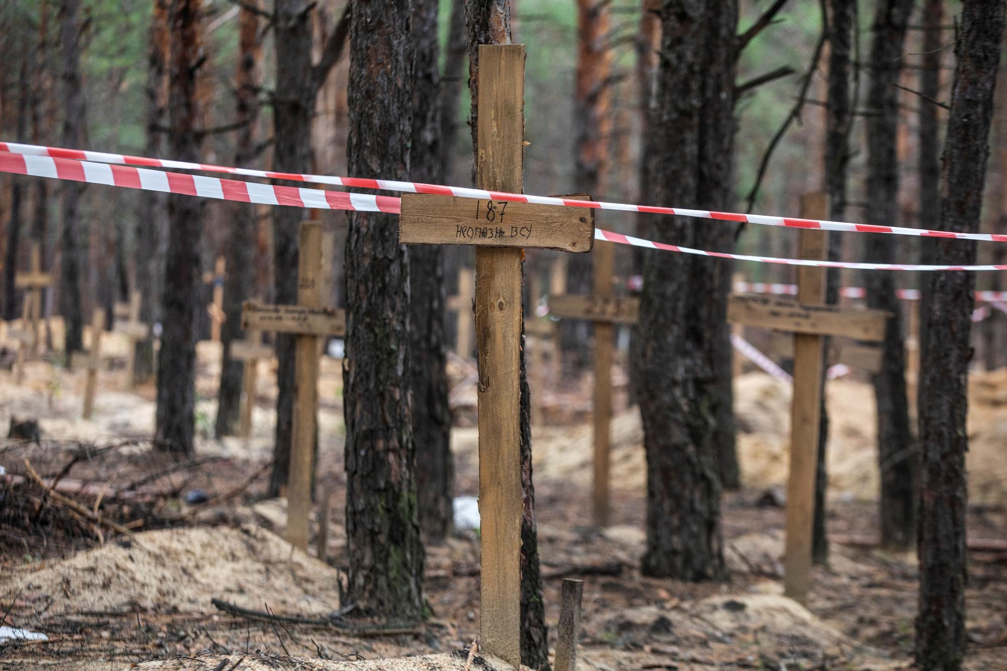 Signal tape is seen over a grave of an unidentified Ukrainian soldier at an improvised cemetery in the town of Izium