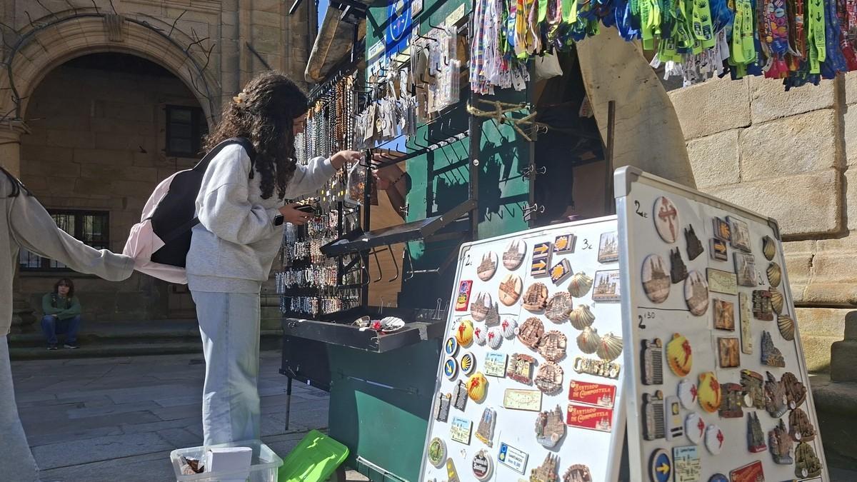 Una joven compra un recuerdo de Santiago en el puesto de Moncho en la Quintana