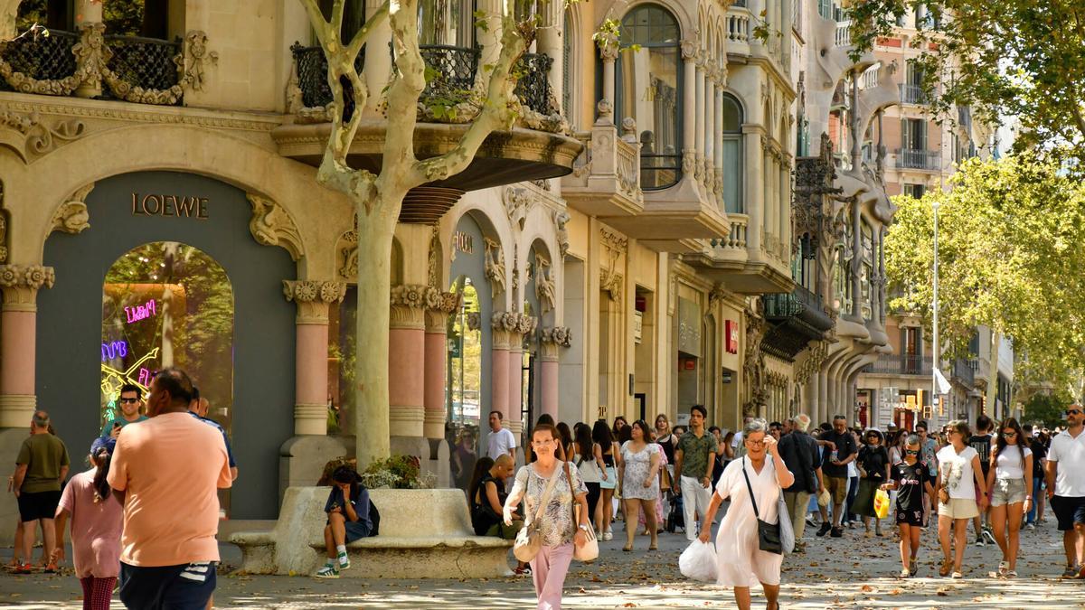 Varios transeúntes pasean por una de las principales zonas comerciales de Barcelona, este verano.